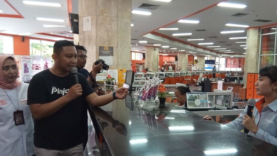CEO Pinjam, Teguh Ariwibowo (dua dari kiri), menjelaskan simulasi proses gadai di counter kantor pos.